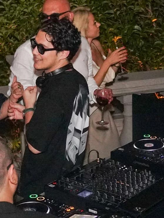 Selim at the DJ decks during an evening set, headphones around his neck.